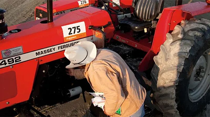 En person granskar motorn på en Massey Ferguson-traktor vid en auktion.