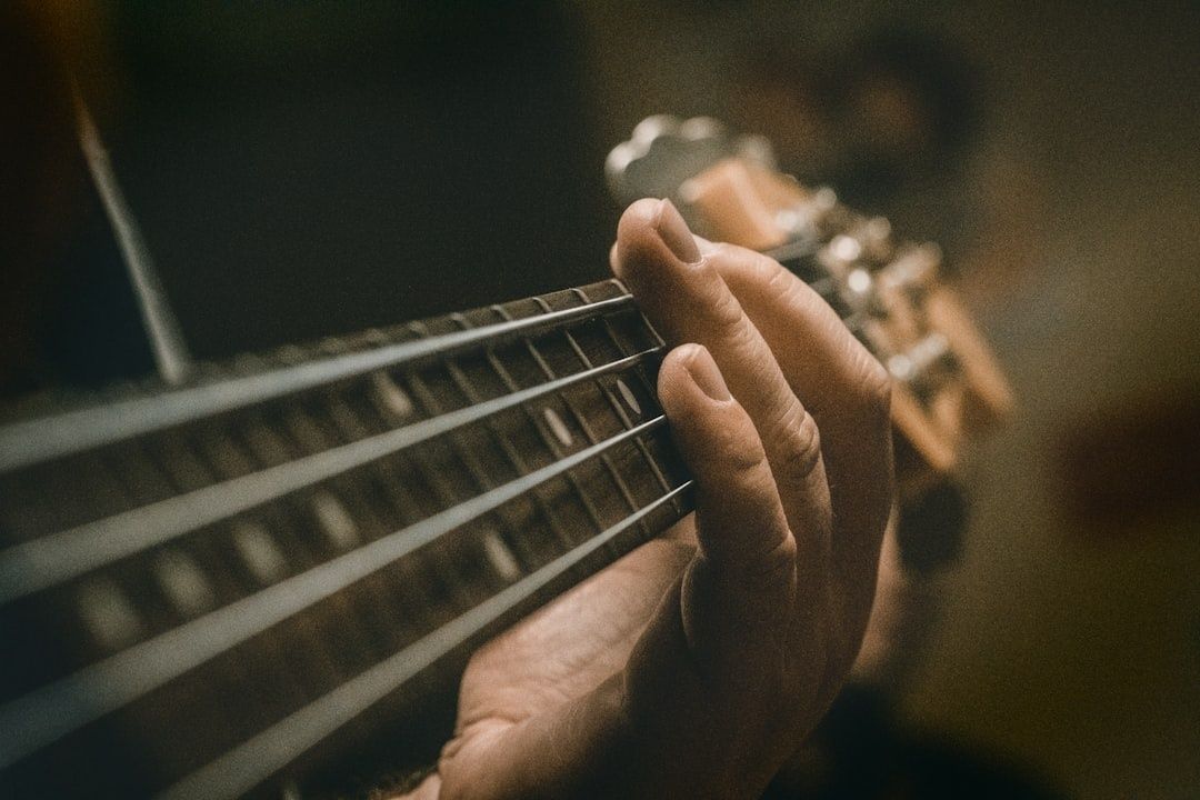 Närbild av en hand som spelar elbas i dämpat scenljus