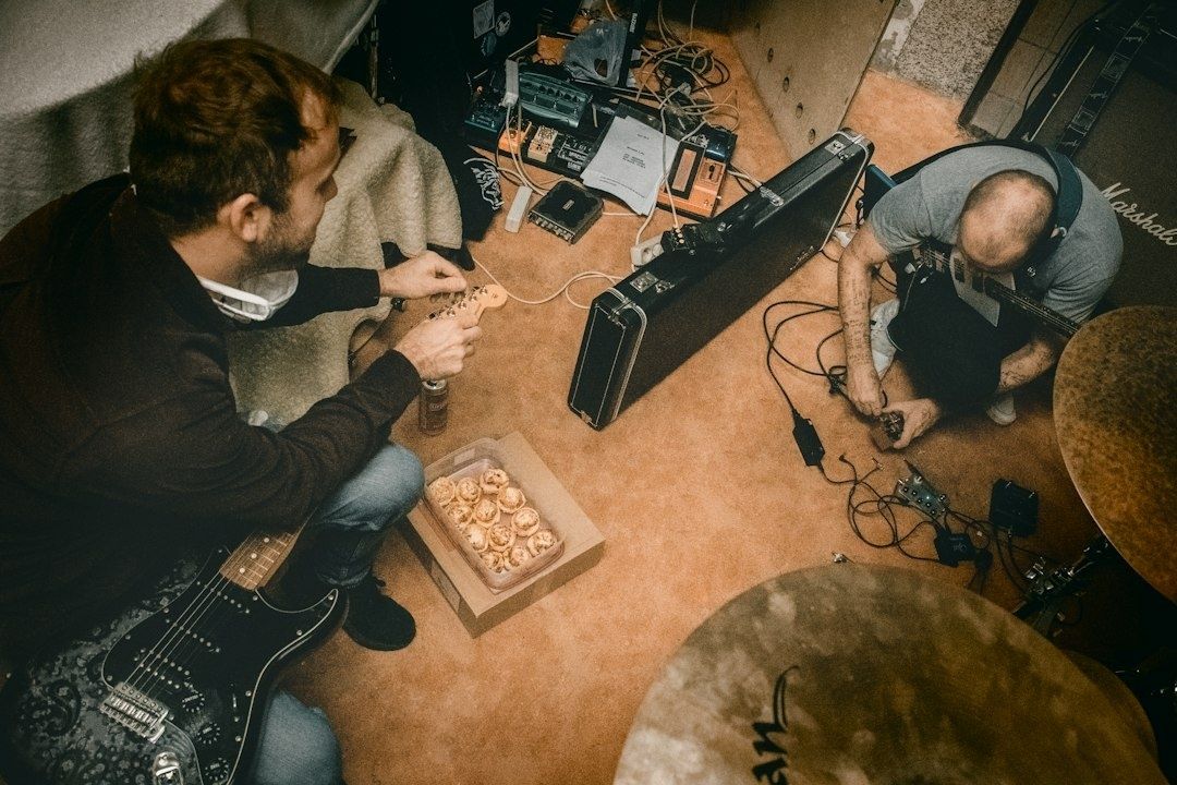 Två musiker arbetar med gitarrer och pedaler i en replokal
